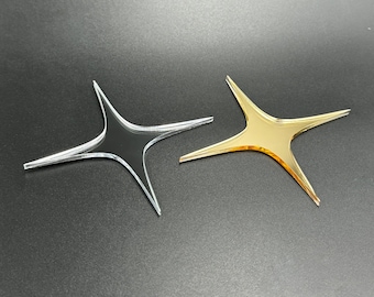 May include: Two star-shaped decorations, one clear and one gold. The clear star is made of acrylic and the gold star is made of metal.