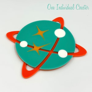 Puede incluir: Un posavasos azul turquesa con un anillo rojo alrededor del borde. El posavasos tiene un diseño de dos estrellas amarillas y tres círculos blancos. El texto "One Individual Coaster" está escrito en negro en la parte superior de la imagen.