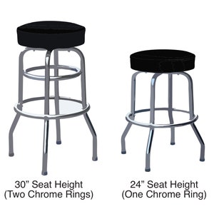 Puede incluir: Dos taburetes de bar de metal con asientos acolchados negros. El taburete de la izquierda tiene dos anillos cromados y una altura de asiento de 76 cm. El taburete de la derecha tiene un anillo cromado y una altura de asiento de 61 cm.