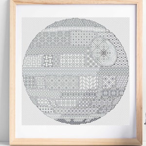 May include: A framed cross-stitch design of the Death Star from Star Wars. The Death Star is made up of a variety of geometric patterns in black and white.