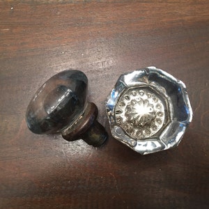 May include: Two antique glass door knobs. One is round and clear, the other is octagonal and has a starburst pattern.