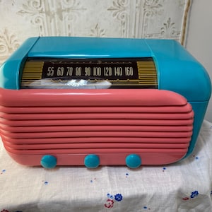 Puede incluir: Una radio vintage turquesa y rosa con un dial que lee 55 60 70 80 90 100 120 140 160.