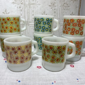 May include: Set of six white ceramic mugs with floral patterns. The mugs feature different floral designs in shades of blue, orange, and yellow.