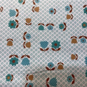 May include: White fabric with a repeating floral pattern. The design features teal and brown flowers with green stems and leaves. Small teal floral shapes fill the background, creating a textured appearance.