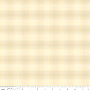 May include: A close-up of a fabric with a small, light yellow grid pattern. The fabric has a subtle texture and a consistent design. The bottom of the image shows an inch ruler.