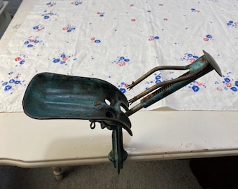 Puede incluir: Un pelador de manzanas vintage de metal verde, de manivela, con un mango de metal y una base de metal.