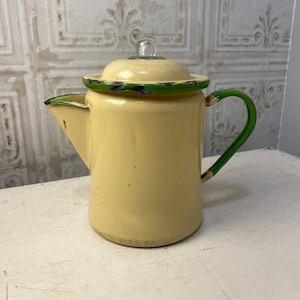 May include: A yellow enamel coffee pot with a green rim and handle. The pot has a glass lid with a knob on top.