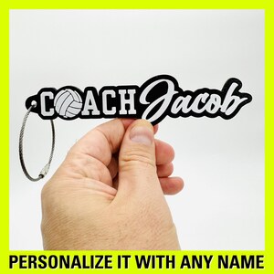 May include: Black keychain with a white volleyball and the text "COACH Jacob" in white lettering. The keychain has a silver metal ring.