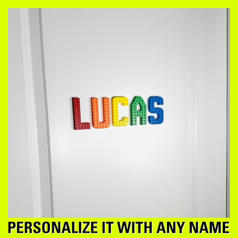 May include: A white door with the name "LUCAS" spelled out in colorful plastic letters. The letters are made to look like LEGO bricks. The text "PERSONALIZE IT WITH ANY NAME" is at the bottom of the image.