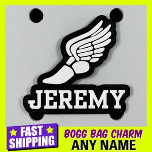 May include: Black and white personalized Bogg Bag charm with a winged running shoe and the name "JEREMY".