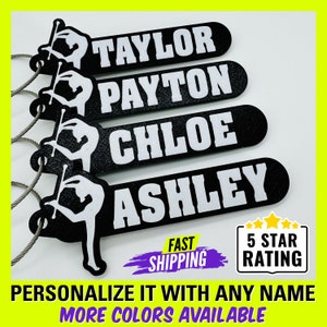 May include: Four black and white personalized keychains with a silhouette of a twirling baton twirler. The keychains feature the names Taylor, Payton, Chloe, and Ashley. The text "FAST SHIPPING" and "5 STAR RATING" are also visible.