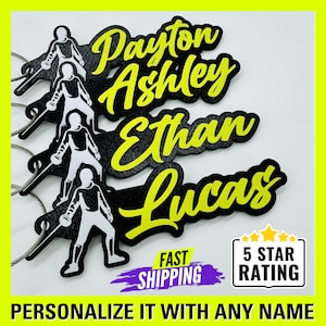 May include: Four black and yellow personalized name tags with a white silhouette of a person fencing. The names on the tags are Payton, Ashley, Ethan, and Lucas.