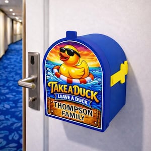 May include: A blue mailbox-shaped container with a yellow duck wearing sunglasses on the front. The duck is floating in water with a life preserver. Text on the front reads "Take a Duck, Leave a Duck, Thompson Family."