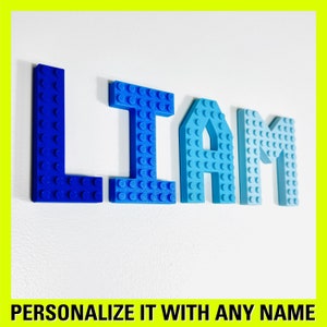 May include: Blue, light blue, and turquoise plastic letters spelling the name "LIAM". The letters are made to look like Lego bricks.