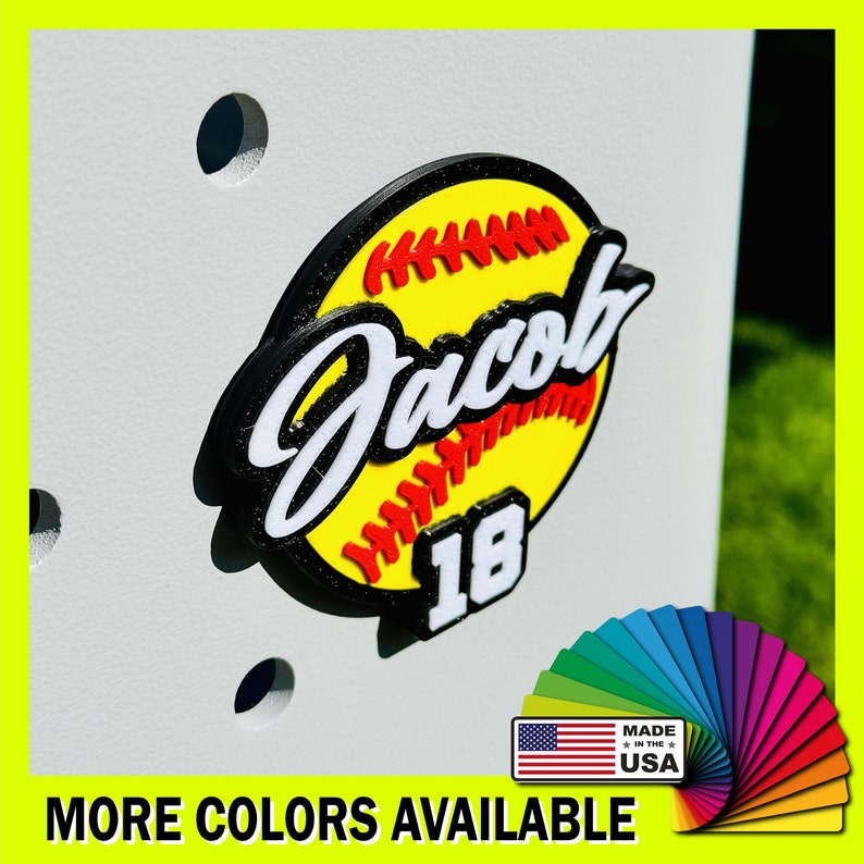 May include: A yellow and black softball with red stitching and the name "Jacob" and the number "18" on it. The softball is on a white background. Made in the USA.