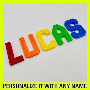 May include: The name "LUCAS" spelled out in colorful plastic letters, each letter a different color of the rainbow. The letters are made to look like Lego bricks.