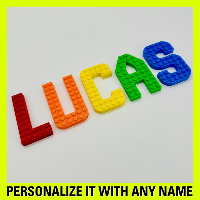 May include: The name "LUCAS" spelled out in colorful plastic letters, each letter a different color of the rainbow. The letters are made to look like Lego bricks.
