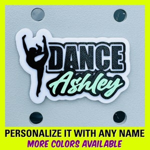 May include: White sticker with black text that says "DANCE" and a black silhouette of a dancer. The name "Ashley" is written in green cursive below the word "DANCE".
