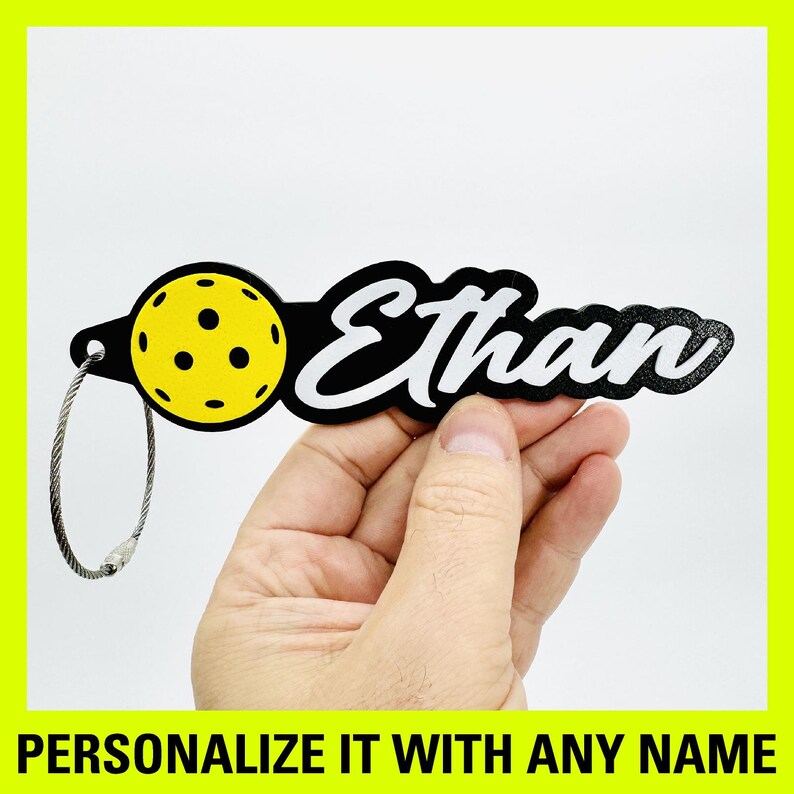 Peut inclure: Porte-cl&eacute;s personnalis&eacute; noir et jaune avec un motif de pickleball et le nom "Ethan".