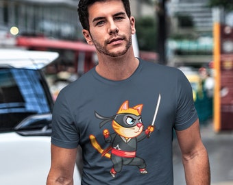 Op de afbeelding: Een marineblauw t-shirt met een cartoonillustratie van een kat die is verkleed als ninja en een zwaard vasthoudt. De kat draagt ​​een zwart masker en een rode sjerp.