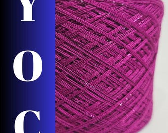 May include: A close-up of a large spool of magenta yarn with a subtle sheen. The yarn is tightly wound, creating a textured surface. The letters "YOC" are vertically stacked on a blue background to the left of the yarn.