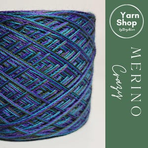 May include: A large spool of Crazy Merino yarn in shades of teal, purple, and black. The yarn is tightly wound, with a visible woven pattern. The image includes the text "Yarn Shop" and "Merino Crazy".