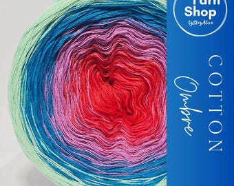 May include: A vibrant ball of ombre cotton yarn, transitioning from light green to blue, purple, and red. The yarn is labeled "Cotton Ombre" with a "Yarn Shop" logo. The colors blend smoothly, creating a visually appealing gradient effect.