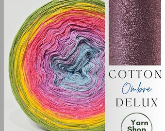 May include: A vibrant ball of Cotton Ombre Deluxe yarn in a rainbow of colors, including green, yellow, pink, blue, and purple. The yarn has a subtle metallic thread running through it. The image also shows a close-up of the yarn's texture and the text "Cotton Ombre Deluxe".