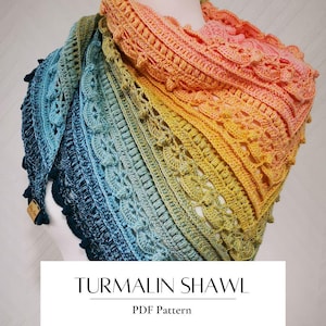 Op de afbeelding: Een handgemaakte, gehaakte sjaal in een kleurengradient van blauw naar geel en oranje. De sjaal heeft ingewikkeld openwerk en een geschulpte rand. De tekst "TURMALIN SHAWL" en "PDF Pattern" staan onderaan.