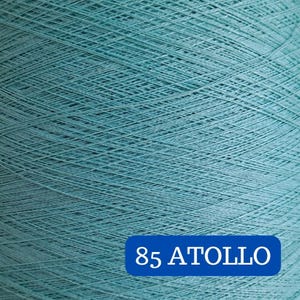 May include: Close-up of a large spool of teal-colored yarn. The yarn is tightly wound, creating a textured surface. A blue rectangle at the bottom displays the text "85 ATOLLO" in white.