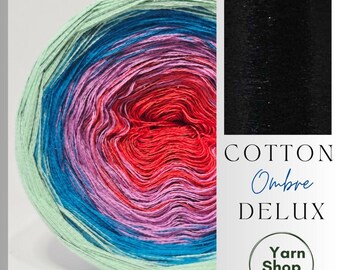 May include: A colorful ball of Cotton Ombre Deluxe yarn. The yarn transitions from light green to blue, pink, and red. The image includes a black swatch and text that reads "Cotton Ombre Deluxe" and "Yarn Shop by Stay Alive."