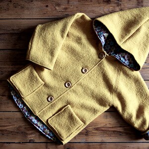 May include: A yellow hooded jacket with a floral patterned lining. The jacket has a button closure and two pockets.