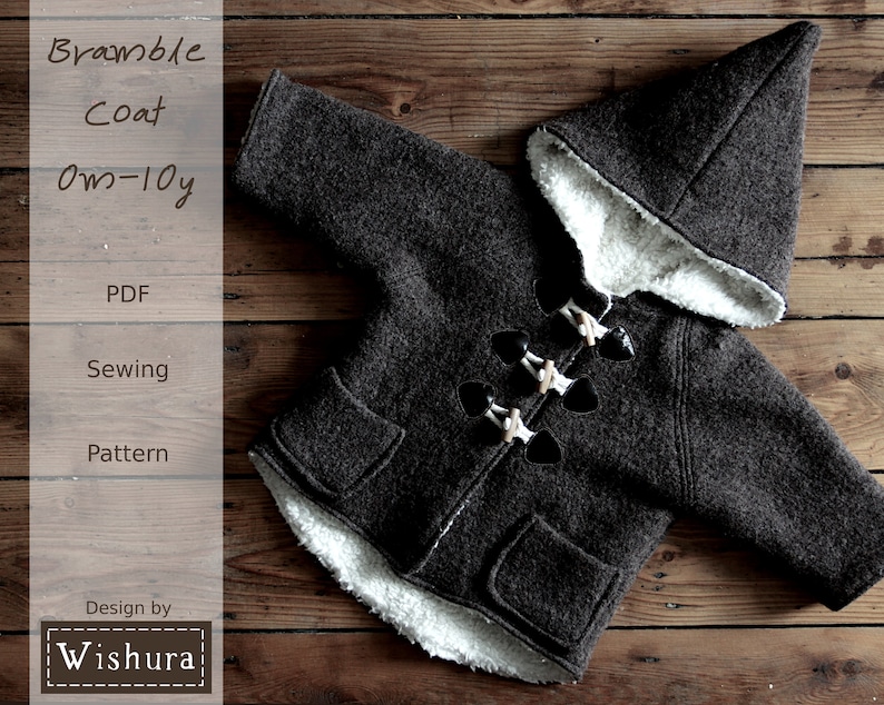 May include: A brown hooded coat with a white fleece lining and toggle closures. The coat is laid out on a wooden surface. The text "Bramble Coat 0m-10y PDF Sewing Pattern Design by Wishura" is visible on the left side of the image.