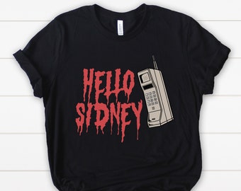 Pode incluir: Camiseta preta com o texto vermelho "HELLO SIDNEY" em fonte gotejante. Um gráfico de telefone celular vintage está à direita. A camiseta é feita de um material macio.