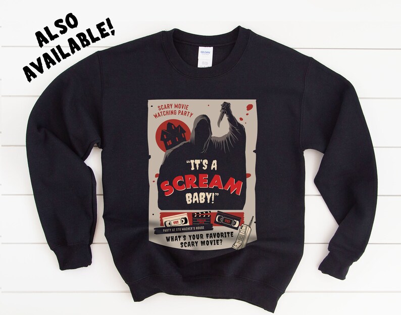 May include: Black sweatshirt with a graphic print of a scary movie poster. The poster features a hooded figure holding a knife and the text "It's a Scream Baby!" and "What's your favorite scary movie?"