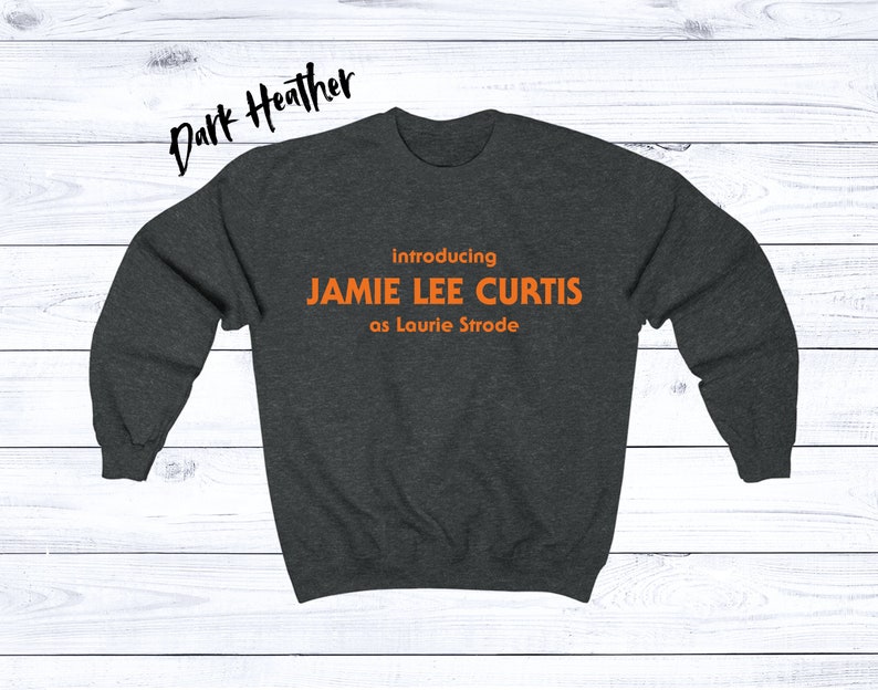 May include: Dark heather grey sweatshirt with the text "introducing JAMIE LEE CURTIS as Laurie Strode" in orange.