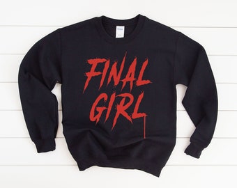 Puede incluir: Sudadera negra con el texto "FINAL GIRL" en rojo, estilizado para parecer sangre goteando.