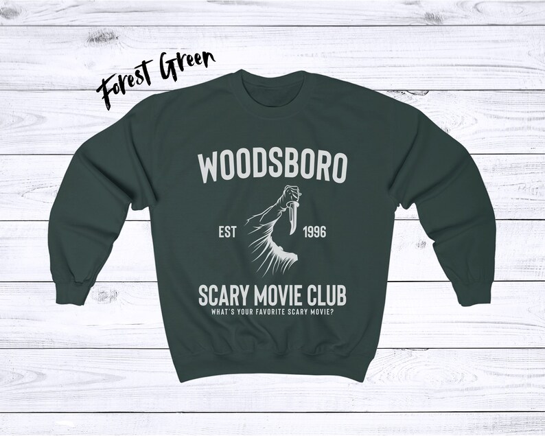 May include: Forest green sweatshirt with the text "WOODSBORO EST 1996 SCARY MOVIE CLUB WHAT'S YOUR FAVORITE SCARY MOVIE?" and a graphic of a hand holding a knife.