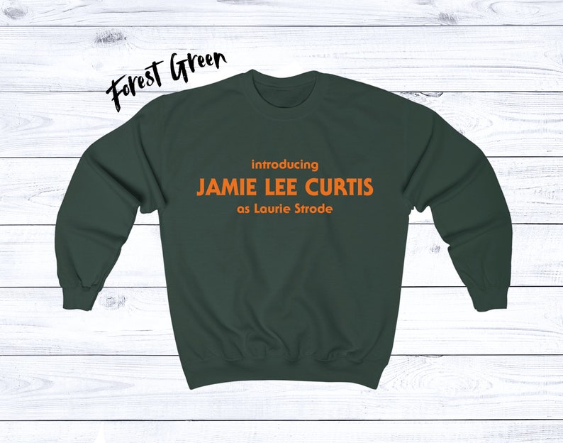 May include: Forest green sweatshirt with the text "introducing JAMIE LEE CURTIS as Laurie Strode" in orange.