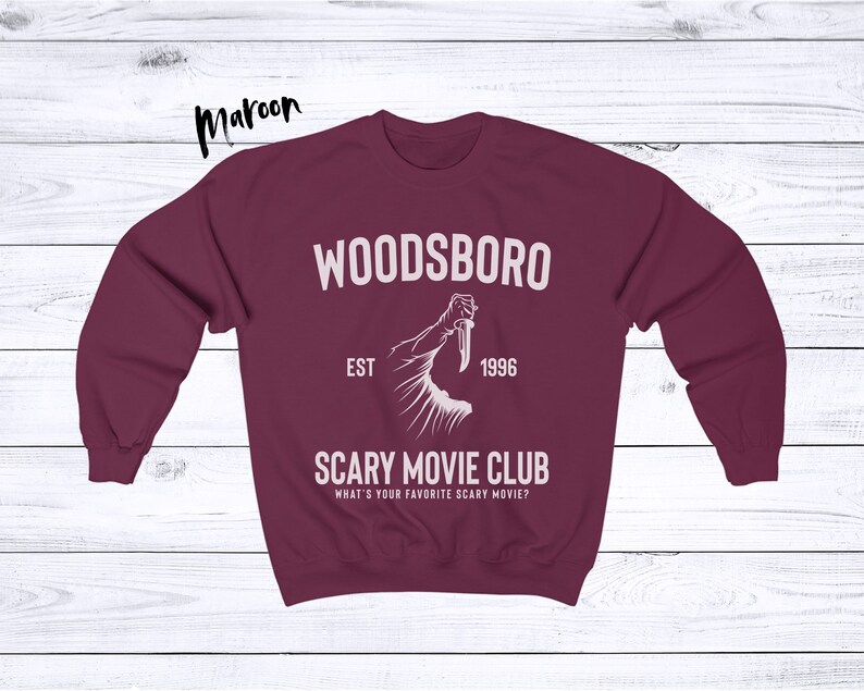 May include: Maroon sweatshirt with white text that reads "Woodsboro Est. 1996 Scary Movie Club What's your favorite scary movie?" and a graphic of a hand holding a knife.