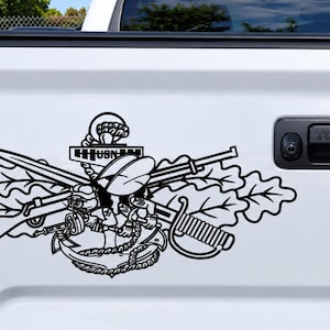 May include: A black vinyl decal applied to a white truck tailgate. The design features a central anchor with the text USN, crossed rifles, a sword, and oak leaves. A small banner on the rifle stock displays the year 1942 in black numerals.