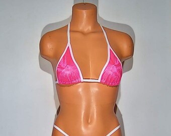 May include: A pink and white bikini top with a lace design. The top has a triangle shape and thin white straps.