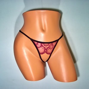 May include: Burgundy lace thong with black trim on a mannequin.