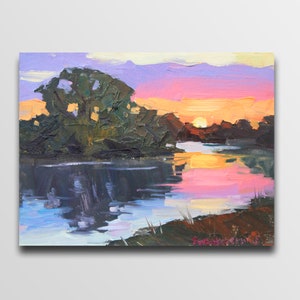 May include: An original oil painting of a sunset over a river. The sky transitions from pink and orange to purple, reflecting in the water. Dark green trees line the riverbank, with the sun setting in the distance.