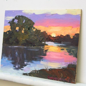 May include: Oil painting of a sunset over a river. The sky transitions from purple to orange, reflecting in the water. Dark green trees line the riverbank, with brushstrokes creating texture and depth. The artwork is on a wooden panel.