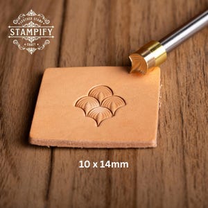 Peut inclure: Un tampon en cuir avec un motif floral décoratif, mesurant 10 x 14 mm (1,0 x 1,4 cm), est pressé sur un morceau de cuir beige. Le tampon est en métal et possède une poignée. Le logo "STAMPIFY" est visible. Outil de création.