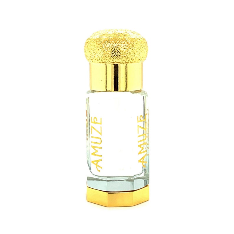 K&ouml;nnte beinhalten: Eine kleine, transparente Glasparf&uuml;mflasche mit goldenen Akzenten. Die Flasche hat einen goldenen Deckel mit strukturiertem Design und einen goldenen Boden. Das Wort "AMUZE" ist vertikal in Gold auf die Flasche gedruckt.
