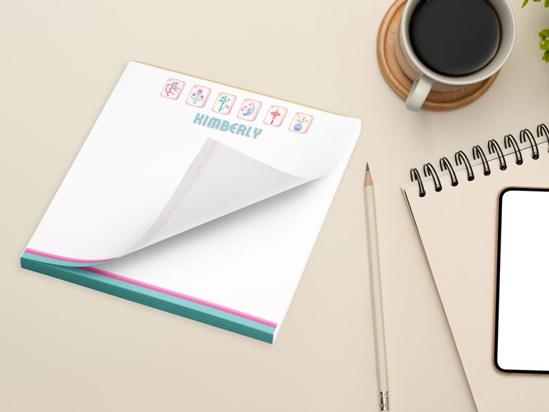 May include: A white notepad with a teal, pink, and white border. The notepad has a personalized name, "KIMBERLY", and a row of colorful Chinese mahjong tiles at the top.