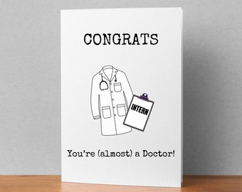 Puede incluir: Una tarjeta blanca con texto negro que dice "CONGRATS" y "You're (almost) a Doctor!"  Una ilustración en blanco y negro de una bata de médico con un estetoscopio y un portapapeles que dice "INTERN" está en la tarjeta.
