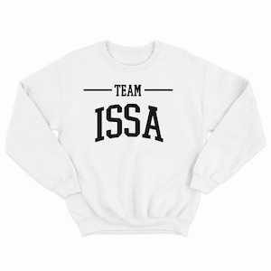 Könnte beinhalten: Weißer Pullover mit schwarzem Text, der auf der Vorderseite "TEAM ISSA" lautet.